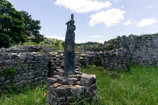 A sculpture of a bird carved from soapstone was temporarily moved from a museum at the same site to be placed back in its original position at the Great Zimbabwe monument near Masvingo on February 20, 2020. - Six of the large carvings were stolen from the ruins of Great Zimbabwe, an imposing stone complex built between the 11th and 13th centuries and attributed to pre-colonial King Munhumutapa. The palatial enclosures are now a UNESCO world heritage site situated in the southeast of Zimbabwe, some 25 kilometres (16 miles) from the present day city of Masvingo. Almost all of the prized green-grey soapstone birds that were looted have now been returned to the country. (Photo by Jekesai NJIKIZANA / AFP)